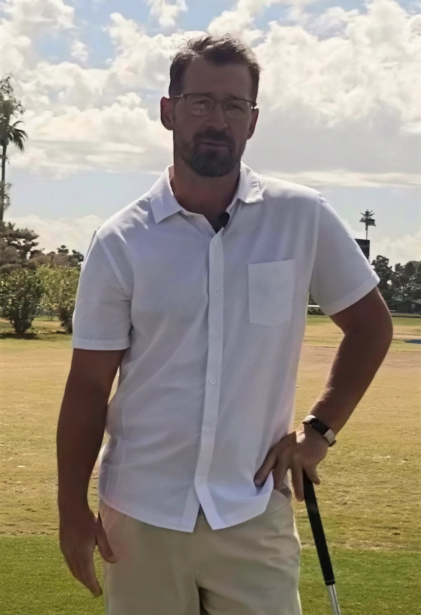 Pat on the practice range, leaning on an iron